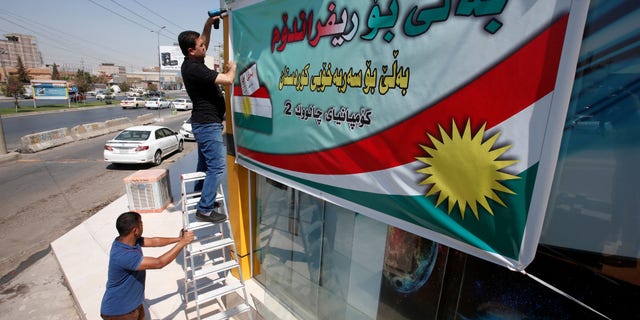 A Kurdish man hangs up a banner, urging people to vote in the September 25th independence referendum, in Erbil, Iraq September 5, 2017.