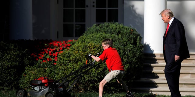 President Trump looks on as 11-year-old Frank Giaccio cuts the Rose Garden grass.