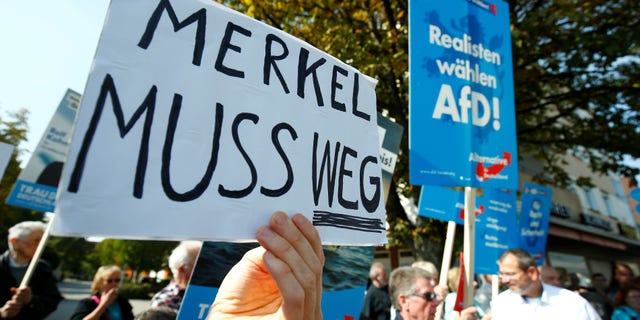 people hold anti-immigration party Alternative fuer Deutschland AfD placards as they protest against German Chancellor Angela Merkel campaigning in Heppenheim, Germany, September 22, 2017.