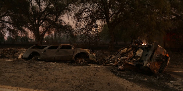 The burned remains of crashed cars are seen at night on a country road as strong winds push the Thomas Fire across thousands of acres near Santa Paula on Tuesday.