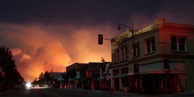 Downtown is darkened by a power outage with smoke rising in the distance in Santa Paula, Calif.