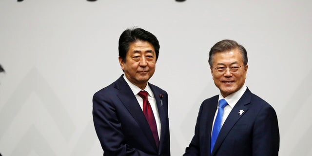Japanese Prime Minister Shinzo Abe, left, greeted by South Korean President Moon Jae-in at the Winter Olympics.