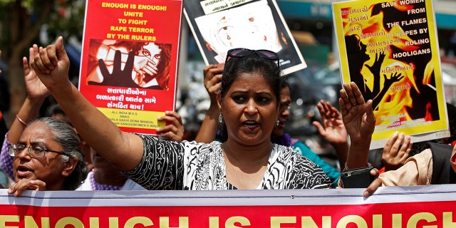People hold placards at a protest against the rape of an eight-year-old girl.