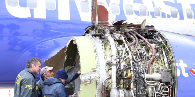 Investigators from the National Transportation Safety Board examine damage to the engine of the Southwest Airlines plane in Philadelphia, April 17, 2018.