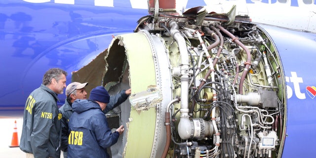 Investigators from the National Transportation Safety Board examine damage to the engine of the Southwest Airlines plane in Philadelphia, April 17, 2018.