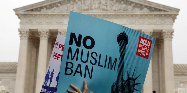 Protesters rally outside the U.S. Supreme Court, while the court justices consider case regarding presidential powers as it weighs the legality of President Trump's latest travel ban.