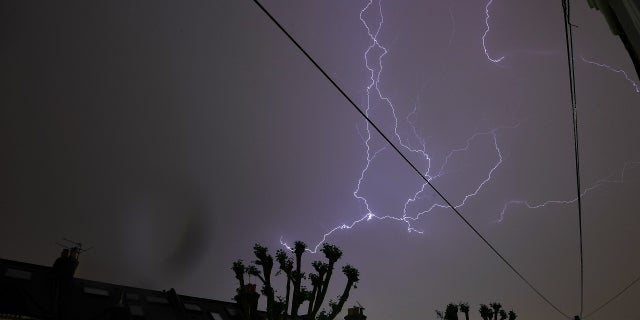 Lightning is seen from a bedroom window as it strikes above a street in south London.