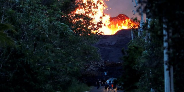 Onlookers gather at the foot of the lava bed, as a lava shoots molten rock into the air, in the Leilani Estates near Pahoa.