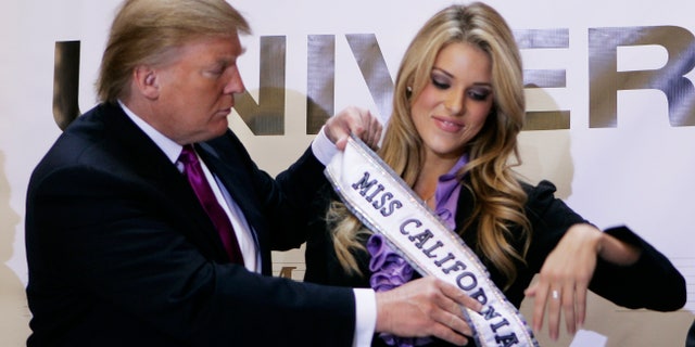 Donald Trump, then owner of the Miss Universe Organization, gives Miss California USA, Carrie Prejean, her sash during a news conference announcing that Prejean would retain her title in New York May 12, 2009.
