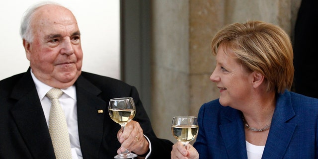 Helmut Kohl toasts with glasses of wine with German Chancellor Angela Merkel.