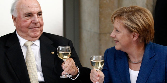 Helmut Kohl toasts with glasses of wine with German Chancellor Angela Merkel.