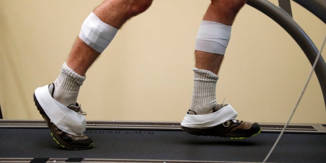 In this Friday, Aug. 12, 2016 photo, sensors are shown taped to the legs and feet of David Moran as he runs on a treadmill in Ann Arbor, Mich