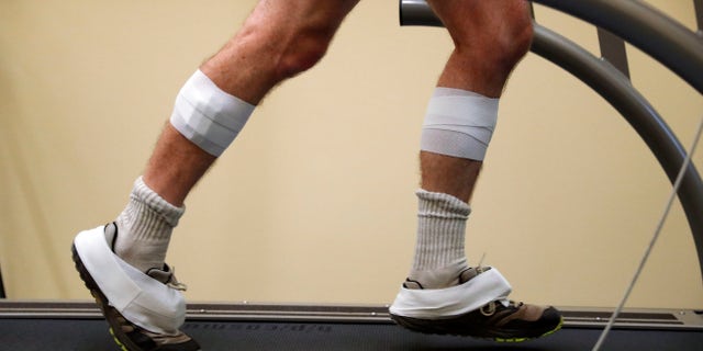 In this Friday, Aug. 12, 2016 photo, sensors are shown taped to the legs and feet of David Moran as he runs on a treadmill in Ann Arbor, Mich