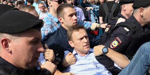 Russian police carrying struggling opposition leader Alexei Navalny, center, at a demonstration against President Vladimir Putin in Pushkin Square in Moscow, Russia, Saturday, May 5, 2018.