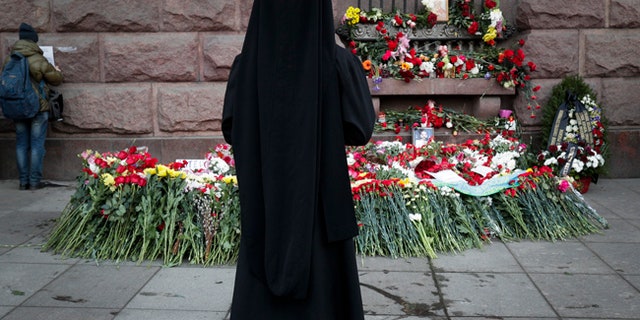 An Orthodox priest stands at a symbolic floral memorial near where a bomb blast tore through a subway train in St. Petersburg, Russia.
