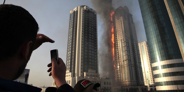 April 3, 2013: A local resident makes photos with a mobile phone of a fire in a high-rise apartment building in provincial capital Grozny, Russia. French actor Gerard Depardieu reportedly received an apartment in the complex of buildings as a gift from Chechen leader Ramzan Kadyrov.