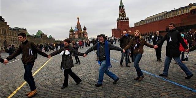 April 8, 2012: Opposition supporters wearing white ribbons walk in a circle hand to hand during a protest at the Red Square in Moscow. Opposition activists called for supporters to walk around Red Square on Sunday wearing the white ribbons that have become a symbol of the protest movement against Prime Minister Vladimir Putin.