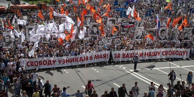 June 12, 2013: Russian opposition protesters some holding portraits of political prisoners  shout anti-Putin slogans as they march through a street next to the Kremlin in Moscow. Thousands of Russian opposition activists are marching through Moscow decrying President Vladimir Putin's authoritarian rule and calling for the release of people they consider political prisoners.