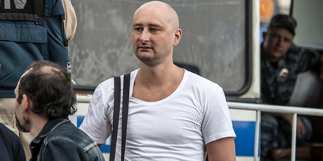 In this photo taken on Friday, May 31, 2013, Arkady Babchenko, 41, who had been scathingly critical of the Kremlin in recent years, stands at a police bus during an opposition rally in Moscow, Russia.