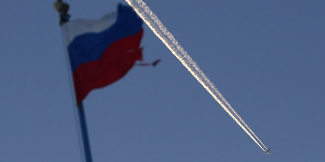 File photo - The Russian state flag flutters, with a plane flying in the sky in the background, outside the Siberian city of Krasnoyarsk, Russia Jan. 27, 2018. (REUTERS/Ilya Naymushin)