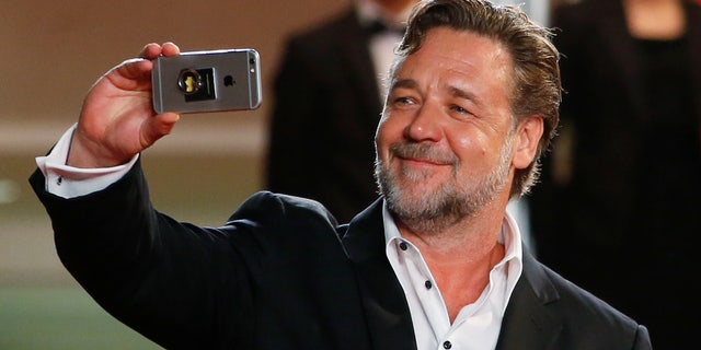 Cast member Russell Crowe uses a smartphone while arriving on the red carpet for the screening of the film "The Nice Guys" out of competition at the 69th Cannes Film Festival in Cannes, France, May 15, 2016. REUTERS/Yves Herman - RTSEFDK