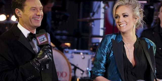 TV host Ryan Seacrest (L) introduces Singer Carrie Underwood on the main stage in Times Square during New Year's Eve celebrations in the Manhattan borough of New York, December 31, 2015. REUTERS/Carlo Allegri - RTX20OYT