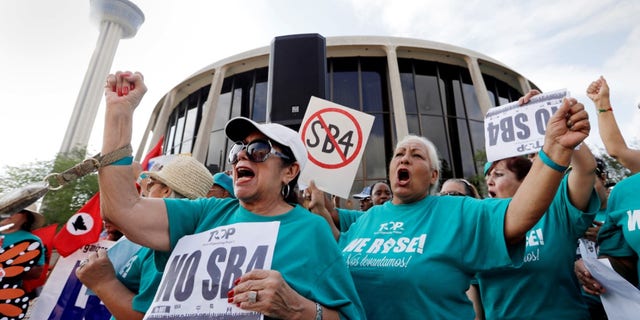 In this June 26, 2017, file photo, Lydia Balderas, left, and Merced Leyua, right, join others as they protest against a new sanctuary cities bill outside the federal courthouse in San Antonio. (AP Photo/Eric Gay, File)