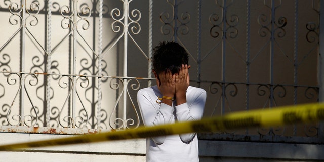 A child covers his face as he stands next to a police cordon at a crime scene where the slain body of a man is found, in Monterrey November 10, 2011. Residents reported that unknown assailants left the body with signs of torture in a park bench, local media reported. REUTERS/Tomas Bravo (MEXICO - Tags: CIVIL UNREST CRIME LAW) - RTR2TURI