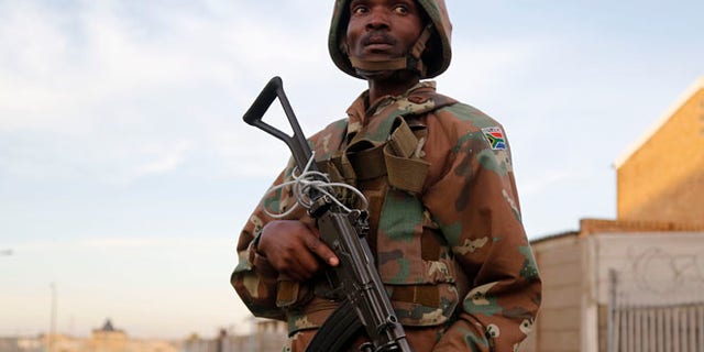 May 21, 2015: A South African soldier provide security for policemen as they look for drugs in Manenberg, South Africa. (AP)