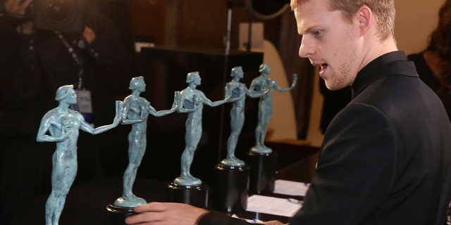 Lucas Hedges, winner of the award for outstanding performance by a cast in a motion picture for "Three Billboards Outside Ebbing, Missouri," examines the SAG Award statues.