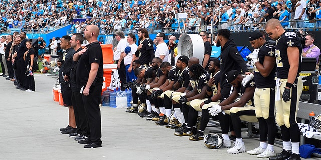 New Orleans Saints players stand and sit during the national anthem at Bank of America Stadium in Charlotte, N.C. on Sept. 24.