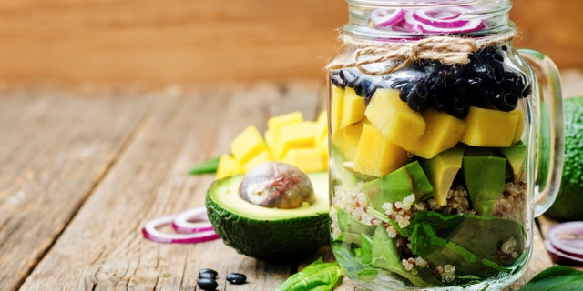 homemade healthy salads with black beans, vegetables, fruits, and quinoa in jar. toning. selective Focus