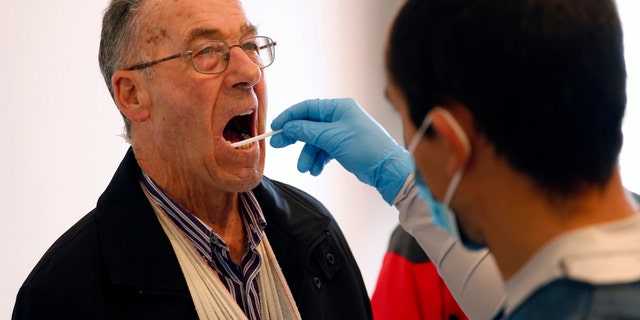 File photo: Gonzalo Carnim, forensic of the Association for the Recovery of Historical Memory (ARMH), takes a saliva sample from a man for a DNA test in Guadalajara's cemetery, Spain, January 22, 2016. (REUTERS/Juan Medina)