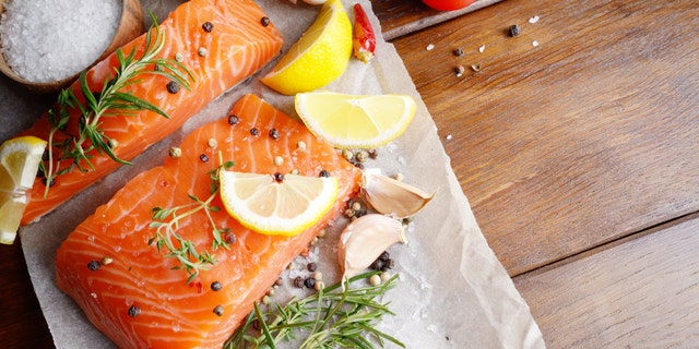 Raw salmon fillet with rosemary pepper sweetbread and salt on baking paper rustic theme with copy-space