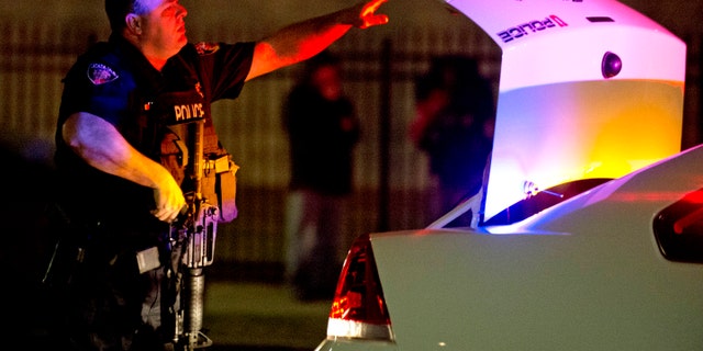 A University of Utah police officer pulls his assault rifle out of the trunk of his squad car as unrest spread throughout Salt Lake City.