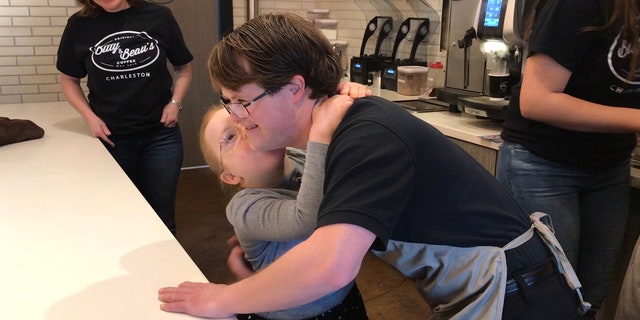 Bitty Wright and Sam Hazeltine hugging behind he counter of Bitty and Beau's Coffee.