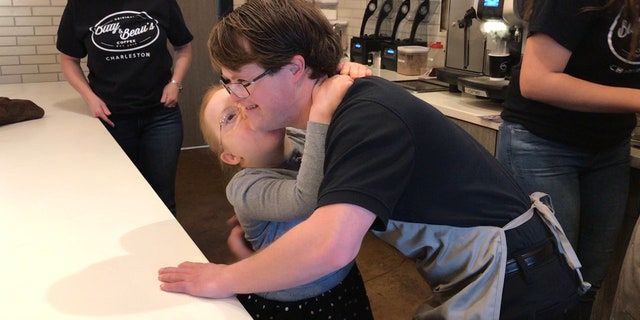 Bitty Wright and Sam Hazeltine hugging behind he counter of Bitty and Beau's Coffee.