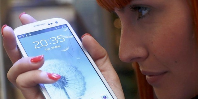 A shop assistant poses with the new Galaxy S III smartphone. Now Samsung wants to get in the social network game.