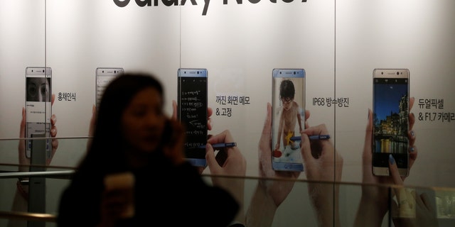 A woman talking on her mobile phone walks past an advertisement promoting Samsung Electronics' Galaxy Note 7 at company's headquarters in Seoul, South Korea, October 11, 2016. (REUTERS/Kim Hong-Ji)