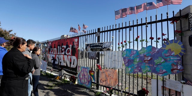 People stand by a make shift memorial for county workers near the Inland Regional Center in San Bernardino, Calif., Friday, Dec. 2, 2016.