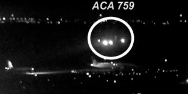 The image shows the Air Canada plane flying just above a United Airlines flight waiting on the taxiway. The jet came within 59 feet of the other planes.