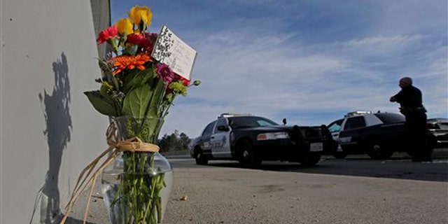 Dec. 3, 2015: Flowers are left by the side of the road as a San Bernardino police officer blocks the road leading to the site of yesterday's mass shooting in San Bernardino, Calif.