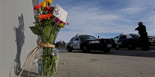Dec. 3, 2015: Flowers are left by the side of the road as a San Bernardino police officer blocks the road leading to the site of yesterday's mass shooting in San Bernardino, Calif.
