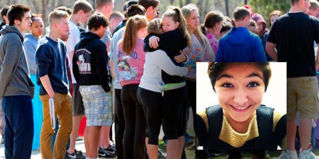 Students hug and spray paint a rock purple outside Jonathan Law High School in Milford, Conn., Friday, April 25, 2014, in memory of 16-year-old stabbing victim Maren Sanchez. Sanchez was stabbed to death earlier in the day during an altercation inside the school. A teenage boy is in custody, and police are investigating whether she was stabbed because she declined to be his date at the junior prom. (AP Photo/The New Haven Register, Peter Hvizdak) MANDATORY CREDIT
