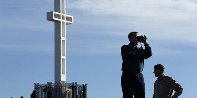 FILE: Jan. 4, 2011: Rev. John Fredericksen of Orlando, Fla., takes a picture in front of the war memorial cross on Mount Soledad in San Diego, alongside Burdette Streeter of San Diego.