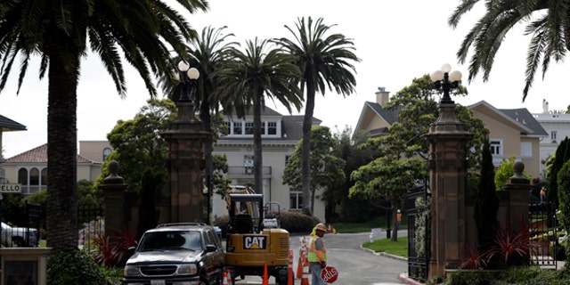 A construction workers stands in front of a gate leading into the Presidio Terrace neighborhood Monday, Aug. 7, 2017, in San Francisco. Thanks to a city auction stemming from an unpaid tax bill, a Bay Area real state investor bought the street in the neighborhood and now owns the sidewalks, the street itself and other areas of "common ground" in the private development that, the San Francisco Chronicle reports, has been managed by the homeowners association since at least 1905. (AP Photo/Marcio Jose Sanchez)
