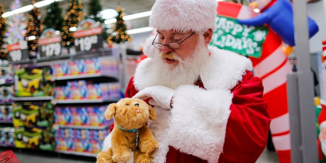 A man dressed as Santa Claus pets a toy as products are display for Christmas season at a Walmart store in Teterboro, New Jersey, U.S., October 26, 2016.