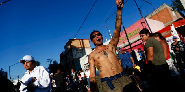 A follower of La Santa Muerte prays near the saint's altar in a Mexico City neighborhood.