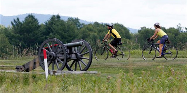 July 2, 2012: Eric Epstien, left, and Isabelle Davidowitz, of Braddock Heights, Md., ride past a cannon on a bike tour of Saratoga National Historical Park in Stillwater, N.Y.