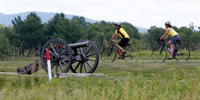 July 2, 2012: Eric Epstien, left, and Isabelle Davidowitz, of Braddock Heights, Md., ride past a cannon on a bike tour of Saratoga National Historical Park in Stillwater, N.Y.